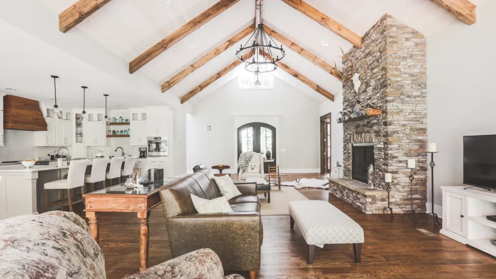 Open-concept living room with vaulted wood-beam ceilings and stone fireplace — W Rondon Construction
